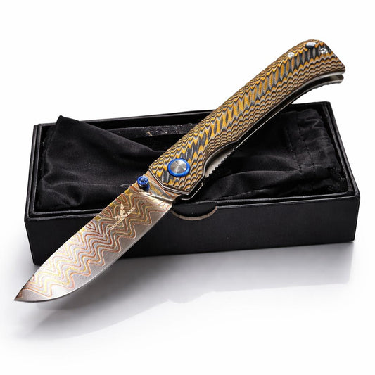 Decorative knife with gold and silver pattern on a black box against a white background